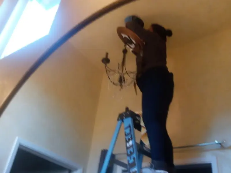 Electrician installing a chandelier in a Burley residence